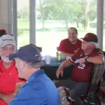 A Group of People Sitting by a Table With a Drink