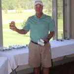 A Man in a Light Blue Top Holding a Trophy