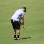 A Man in a Blue Shirt and Black Shorts Playing Golf